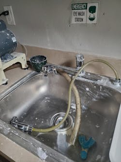 Eye wash station is adjacent to dental laboratory. Water flow through eye wash station valves was occluded by hardened dental stone (plaster), rendering it inoperable.