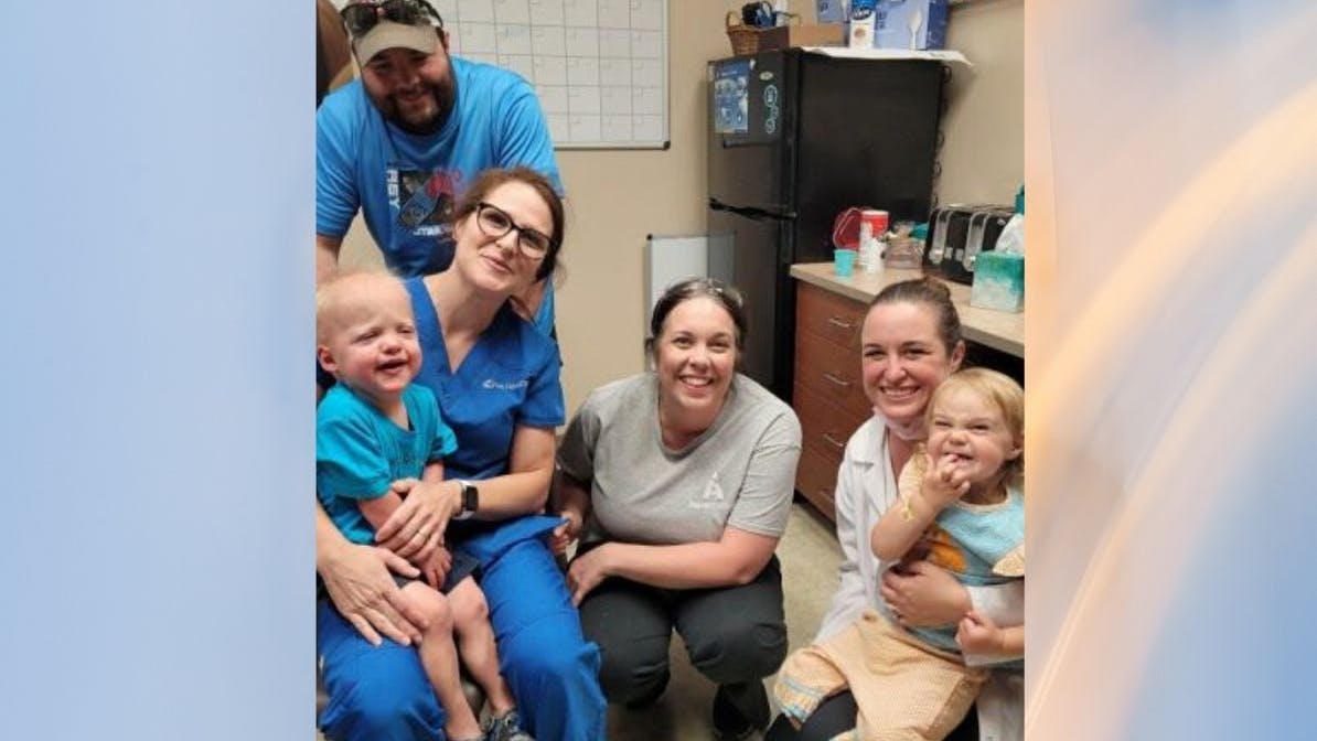 The Emmick family, left: Weston's mother holding him, his father behind them. Center, lab technician Julie Bostwick, and Dr. Deitz, right, holding her daughter. The two used an impression of Dr. Deitz's daughter's teeth to create Weston's dentures.