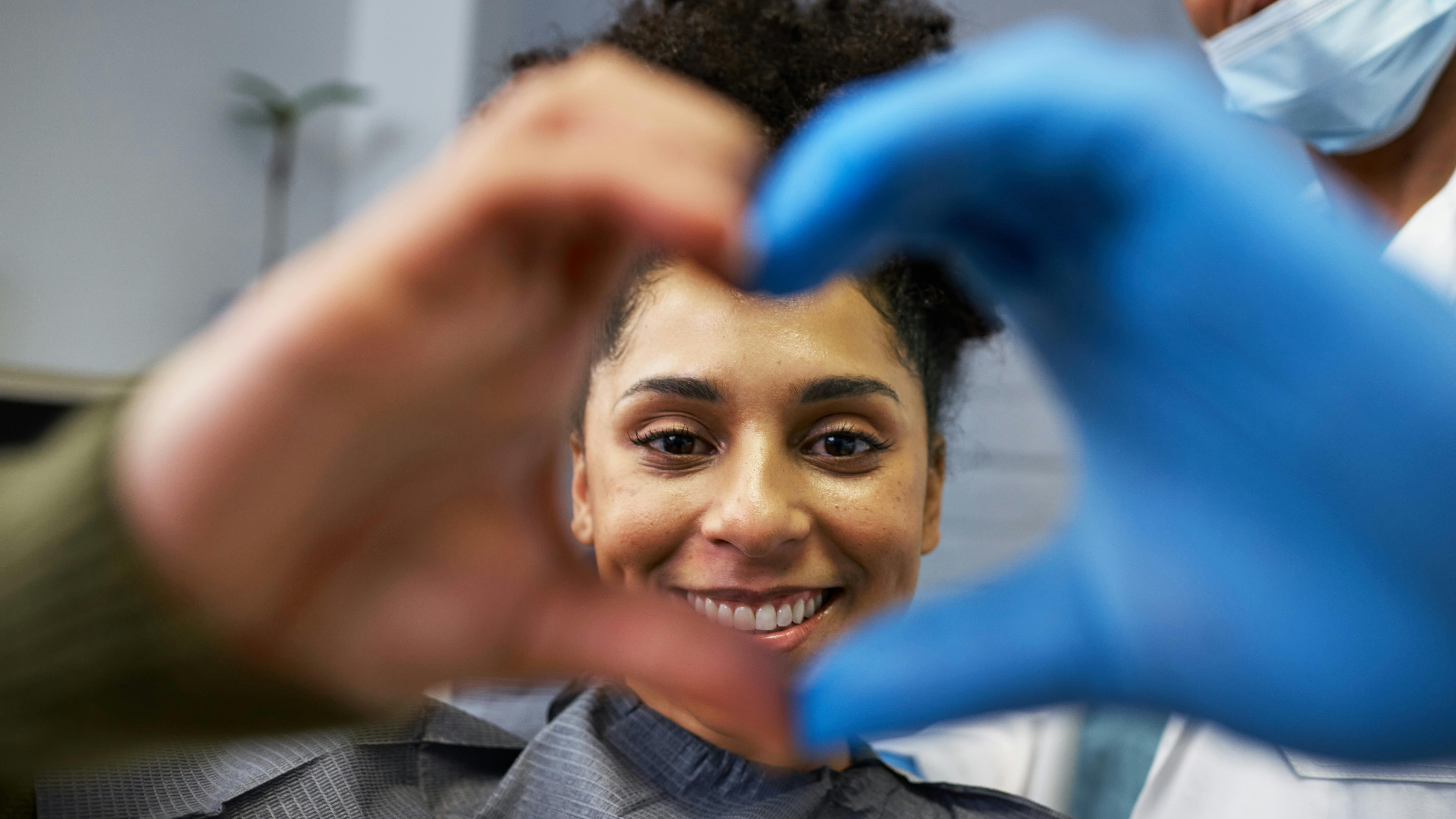Smiling patient makes 'heart hands' with dentist