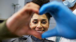 Smiling patient makes 'heart hands' with dentist Smiling patient makes 'heart hands' with dentist