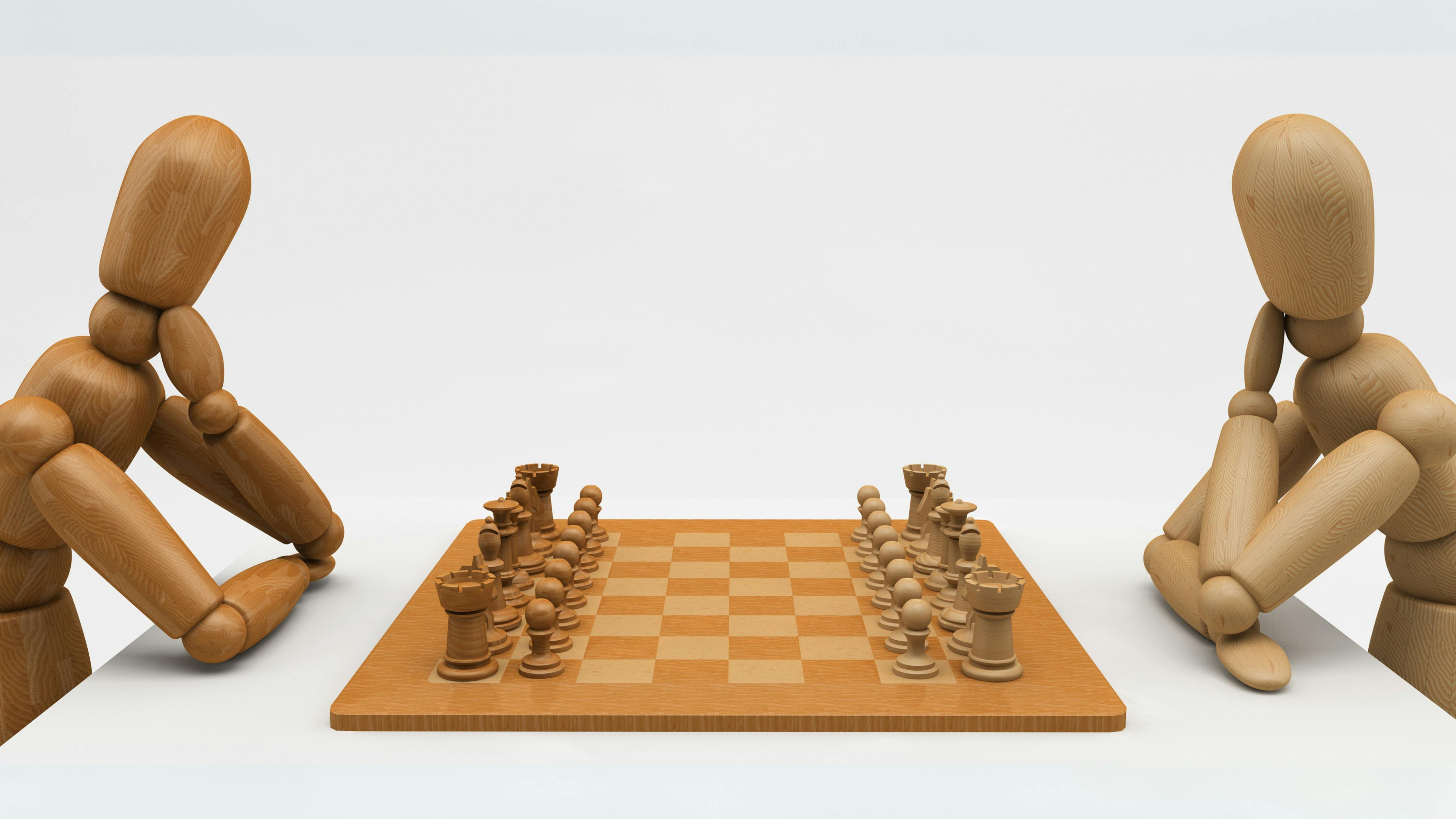Two wooden mannequins playing chess