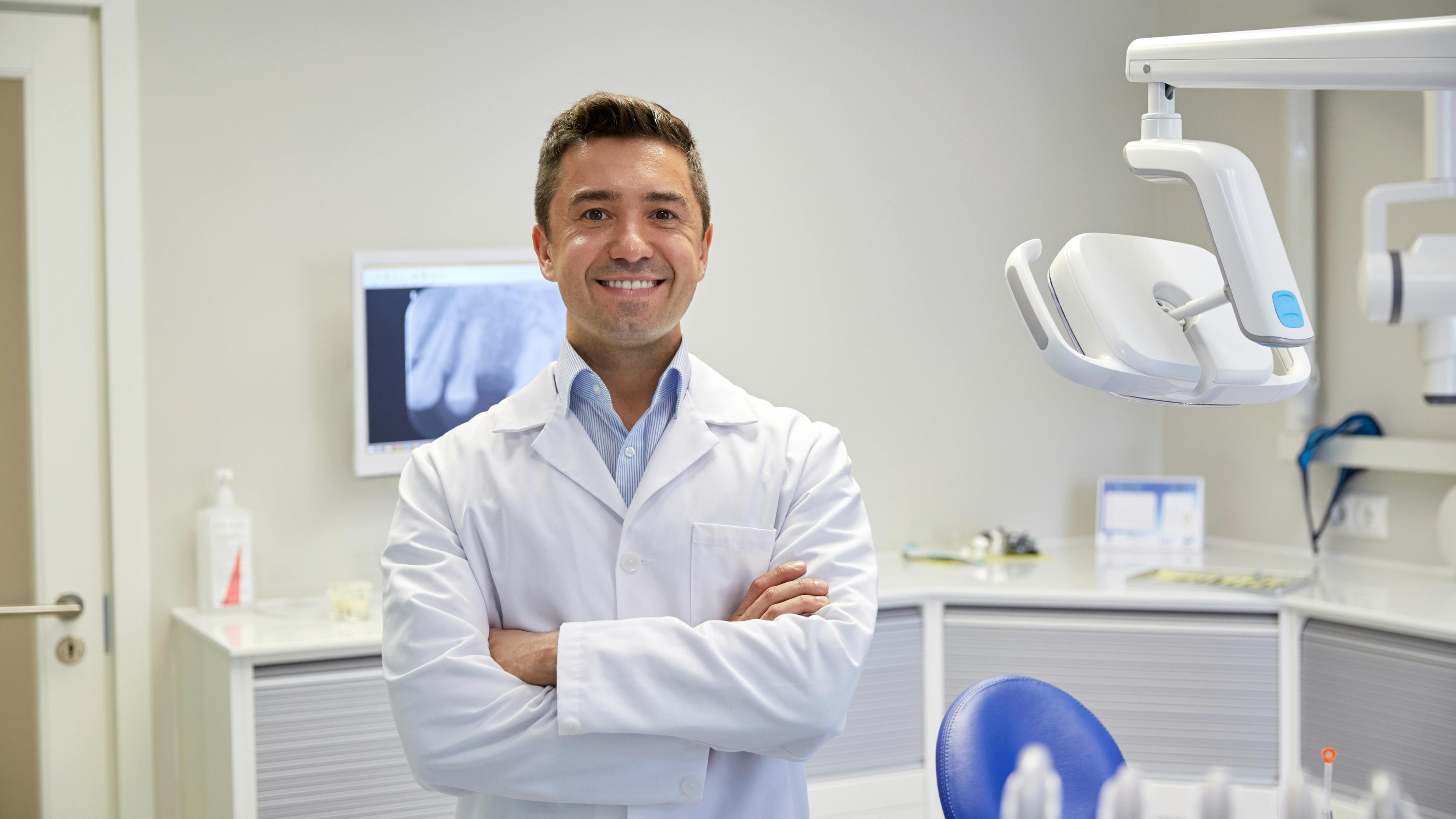 Smiling dentist with arms crossed in dental operatory