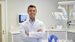 Smiling dentist with arms crossed in dental operatory Smiling dentist with arms crossed in dental operatory