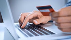 Person using laptop and holding credit card Person using laptop and holding credit card