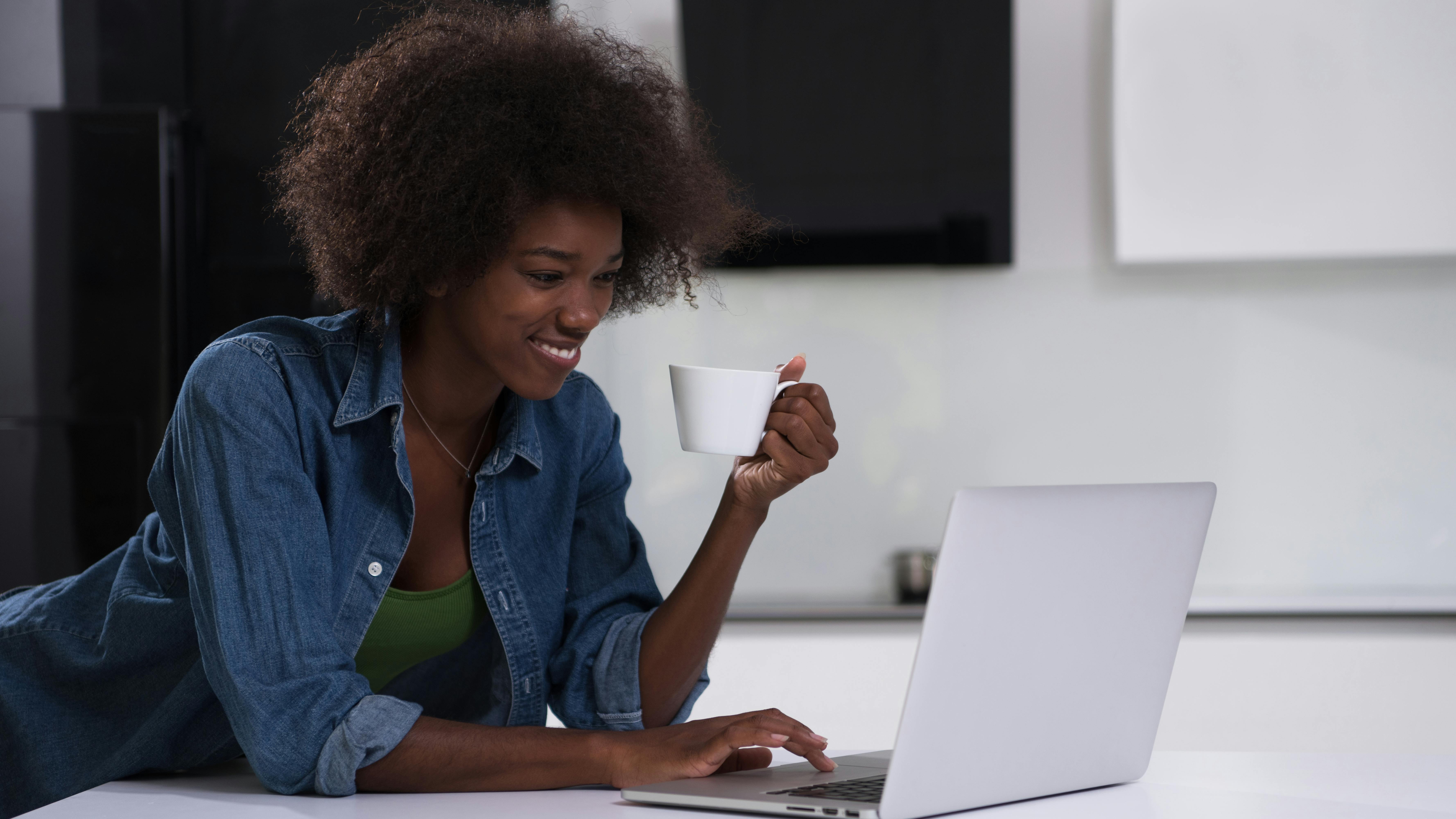 Woman enjoys a cup of coffee while using laptop