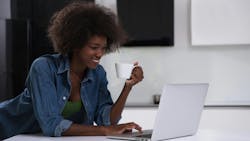 Woman enjoys a cup of coffee while using laptop Woman enjoys a cup of coffee while using laptop