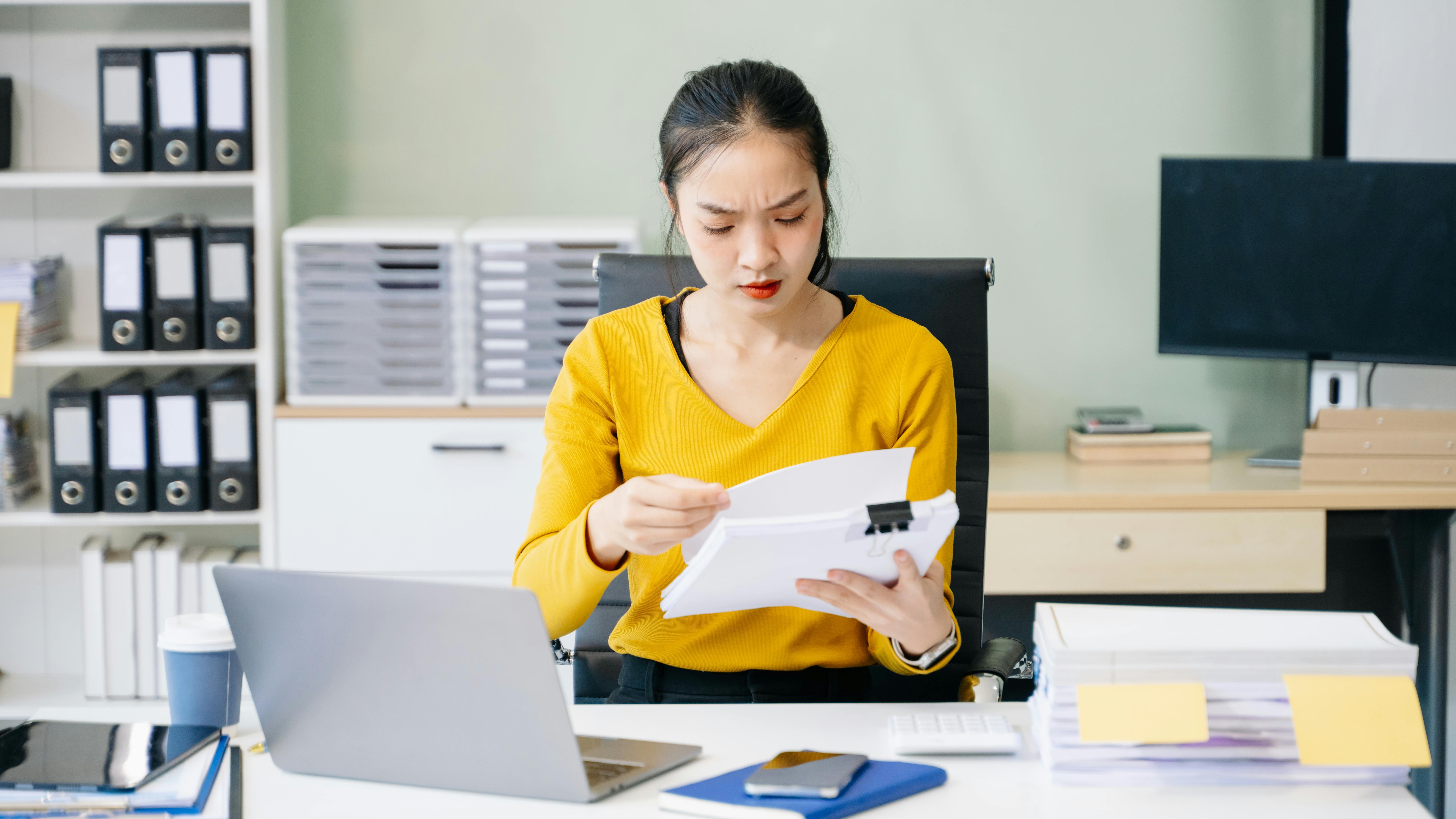 Front desk person frustrated at computer with paperwork