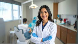 Confident female dentist stands facing the camera in an operatory. Confident female dentist stands facing the camera in an operatory.
