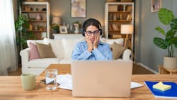 Woman sitting at laptop holding her face in her hands Woman sitting at laptop holding her face in her hands