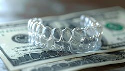 A set of dental clear aligners sitting on top of $100 bills A set of dental clear aligners sitting on top of $100 bills