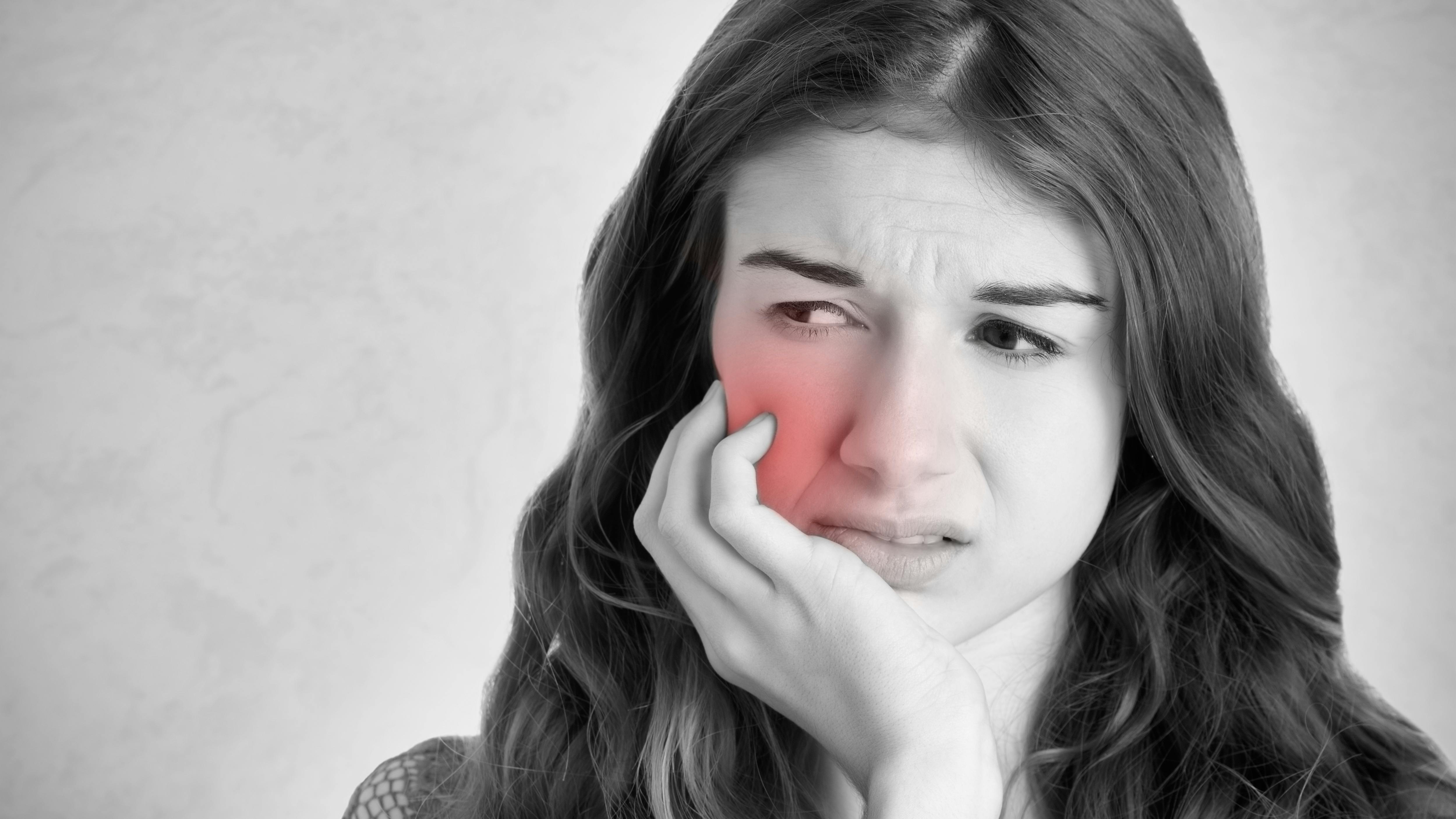 Woman grimacing and grasping jaw