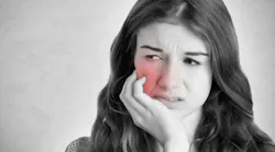 Woman grimacing and grasping jaw