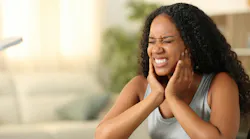 Woman wincing, holding jaw in pain