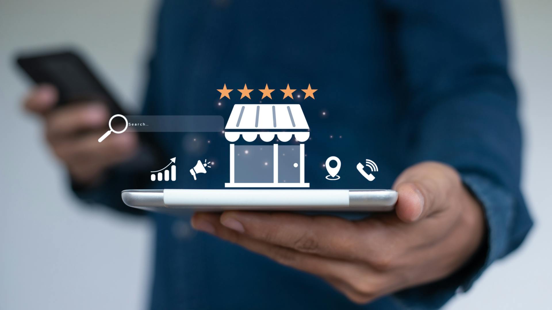 Hand holds electronic tablet with icons of a shop, location pin, telephone, and 5 stars popping up