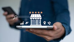 Hand holds electronic tablet with icons of a shop, location pin, telephone, and 5 stars popping up Hand holds electronic tablet with icons of a shop, location pin, telephone, and 5 stars popping up