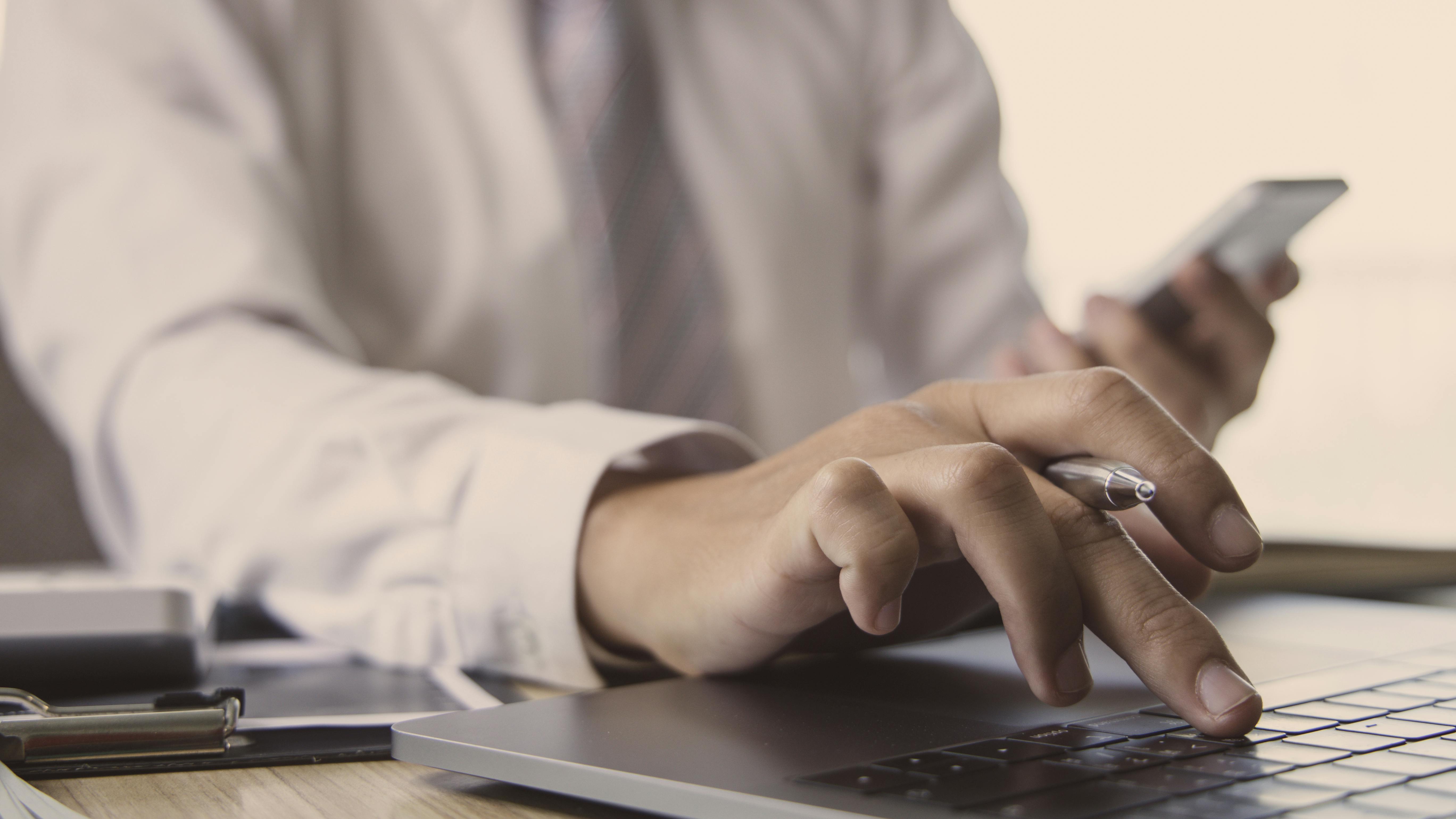 Man sitting at desk reviewing paperwork with pen and calculator