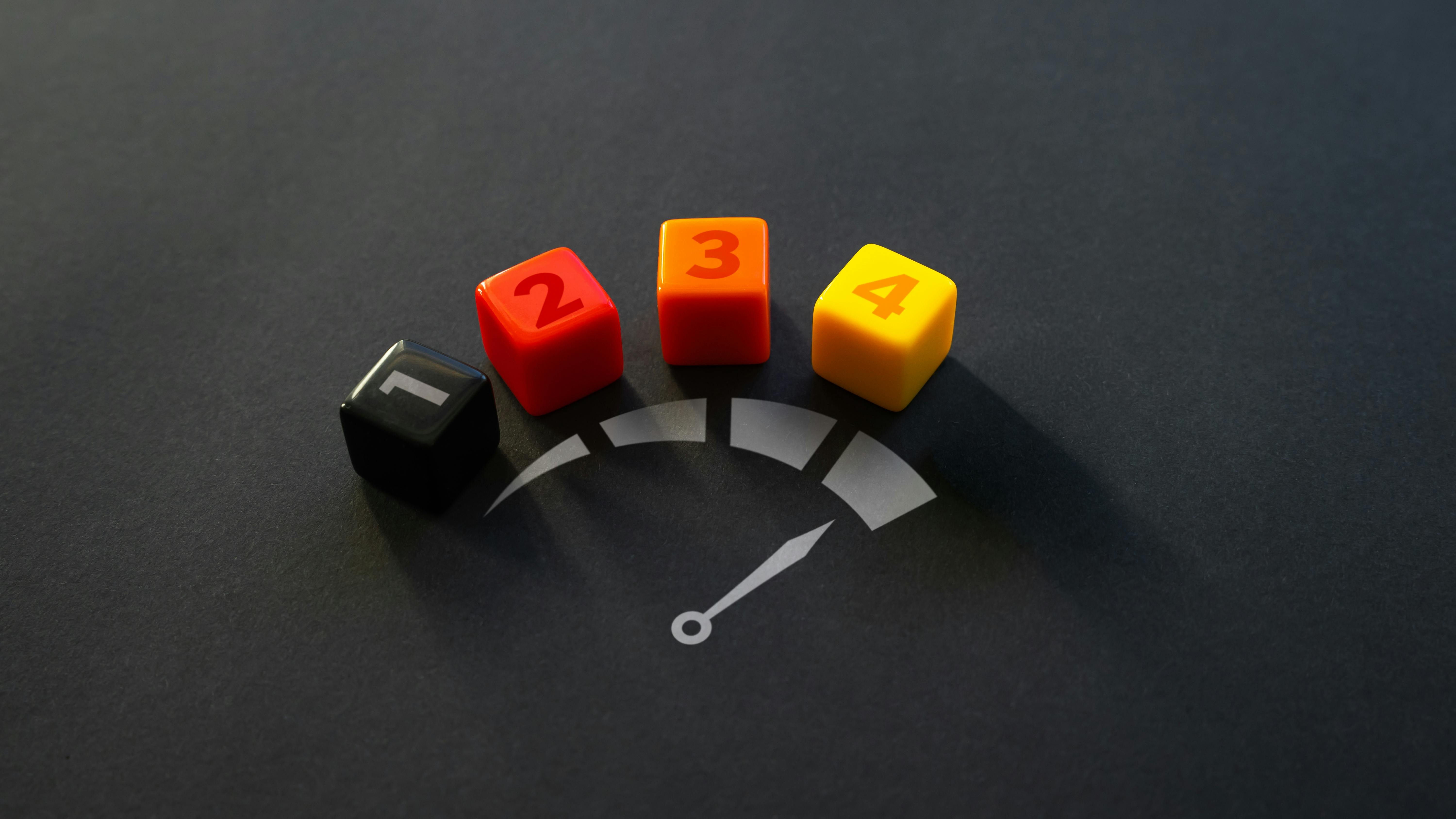 four dice with the numbers 1 through 4 above an illustration of a speedometer