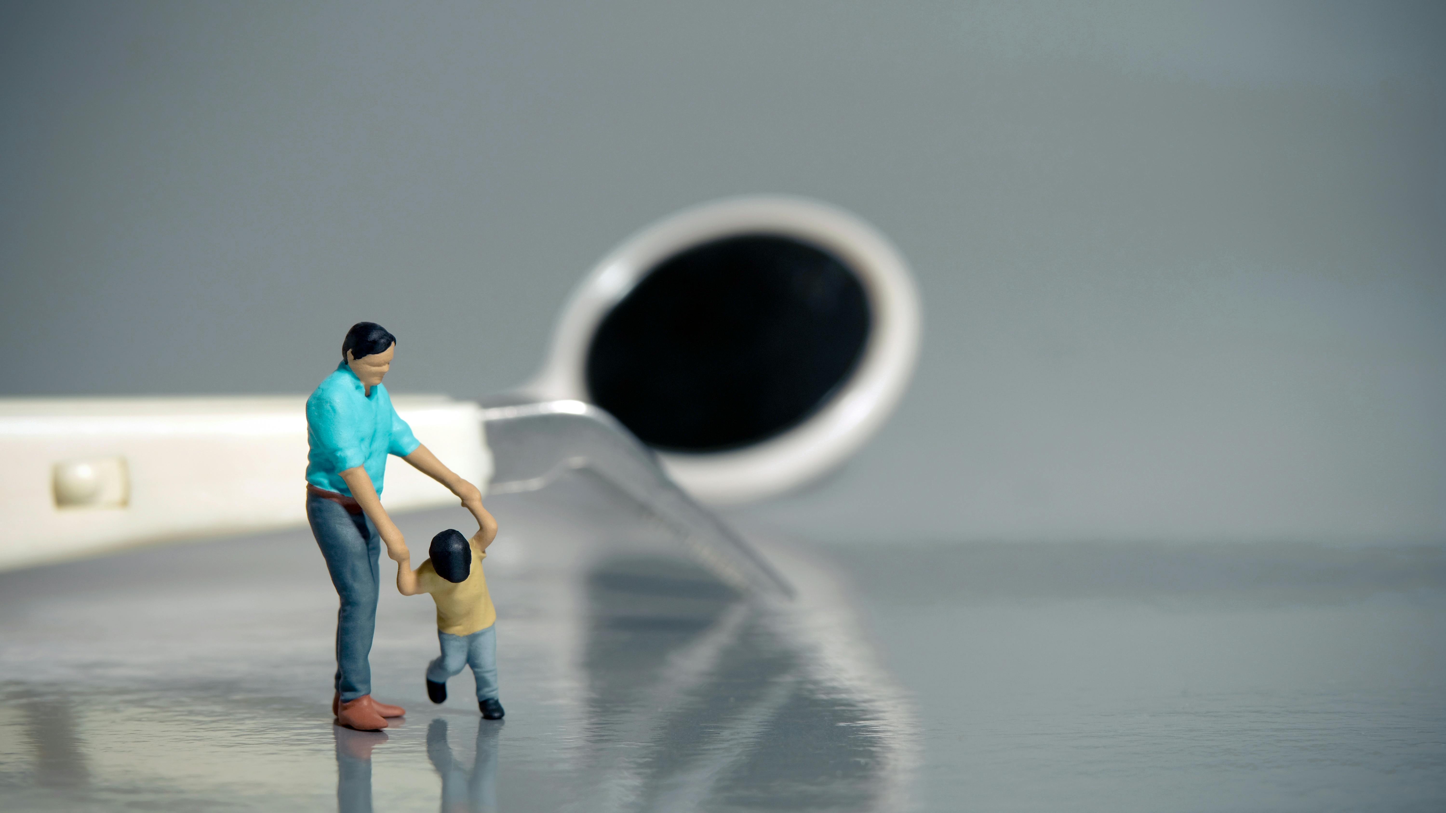 Miniature toy father and child in the foreground with dental instruments behind
