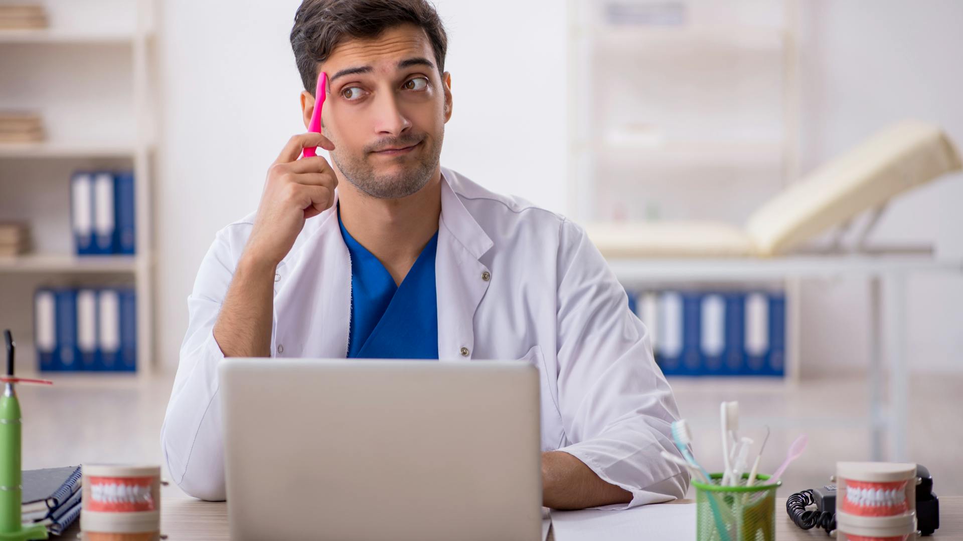 Dentist sitting behind laptop at desk