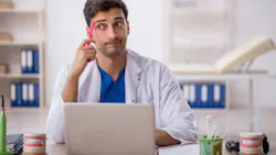 Dentist sitting behind laptop at desk Dentist sitting behind laptop at desk