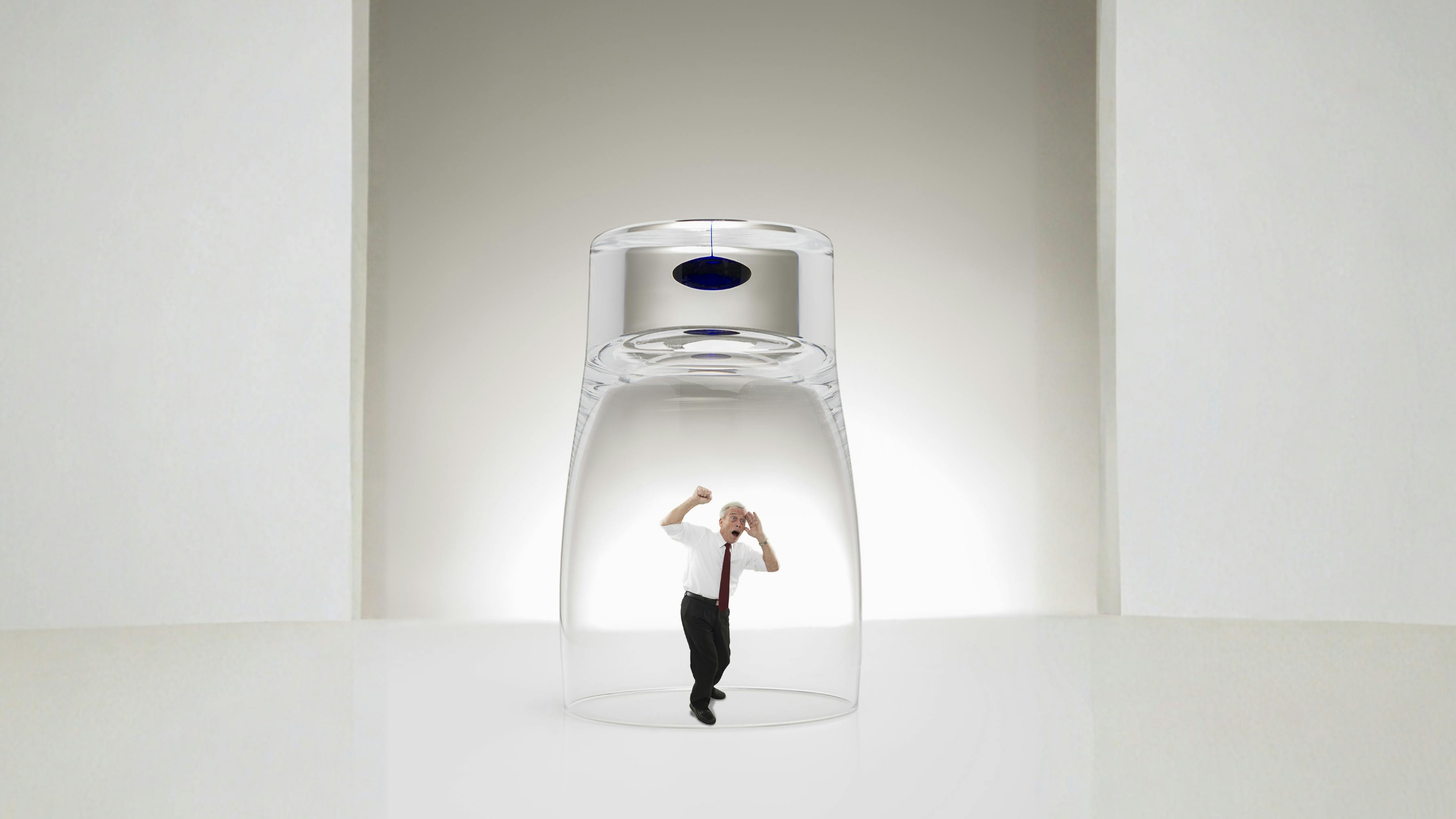 Man trapped underneath a glass on a tabletop