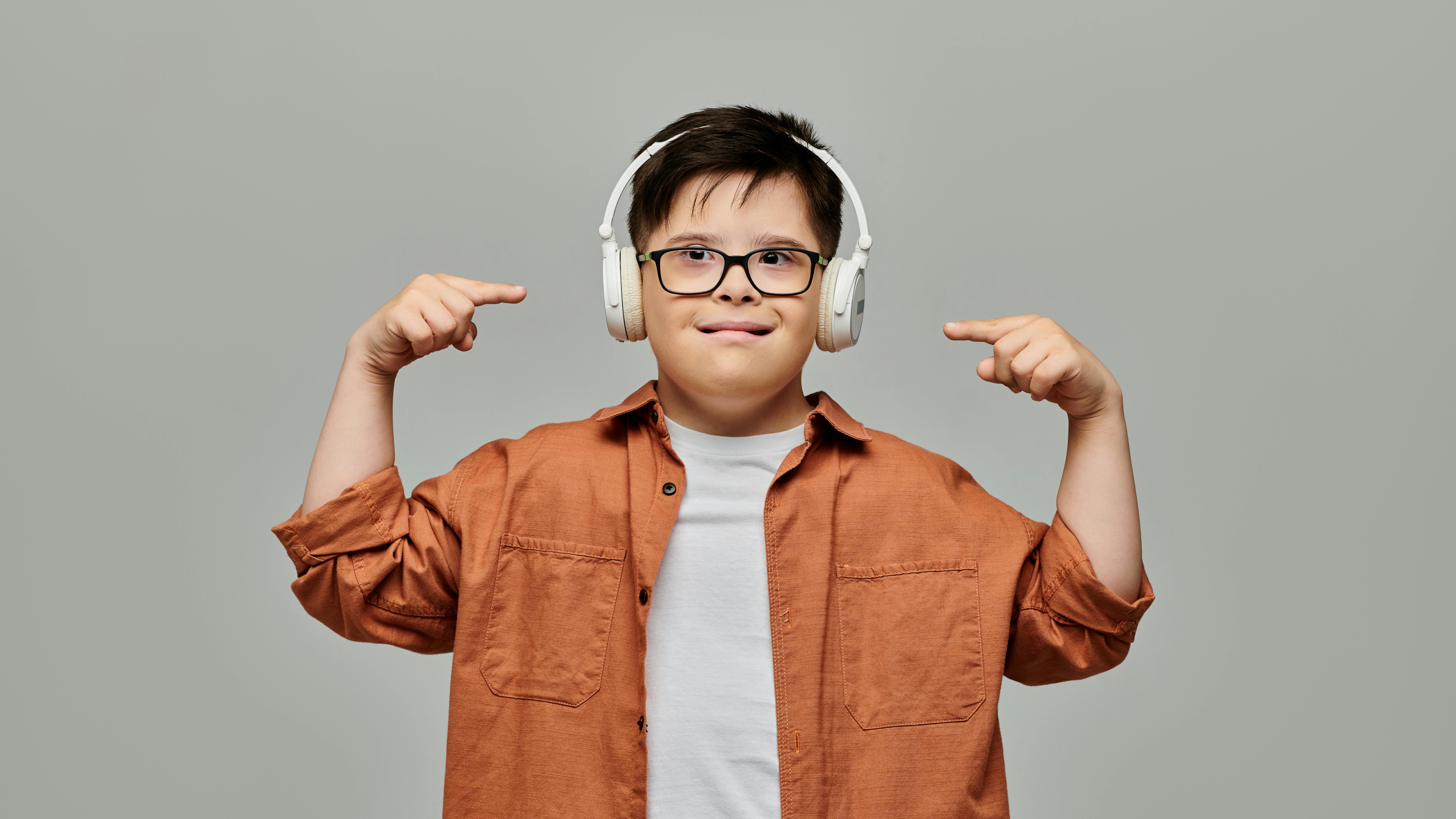 Special needs child smiles and points to headphones he's wearing