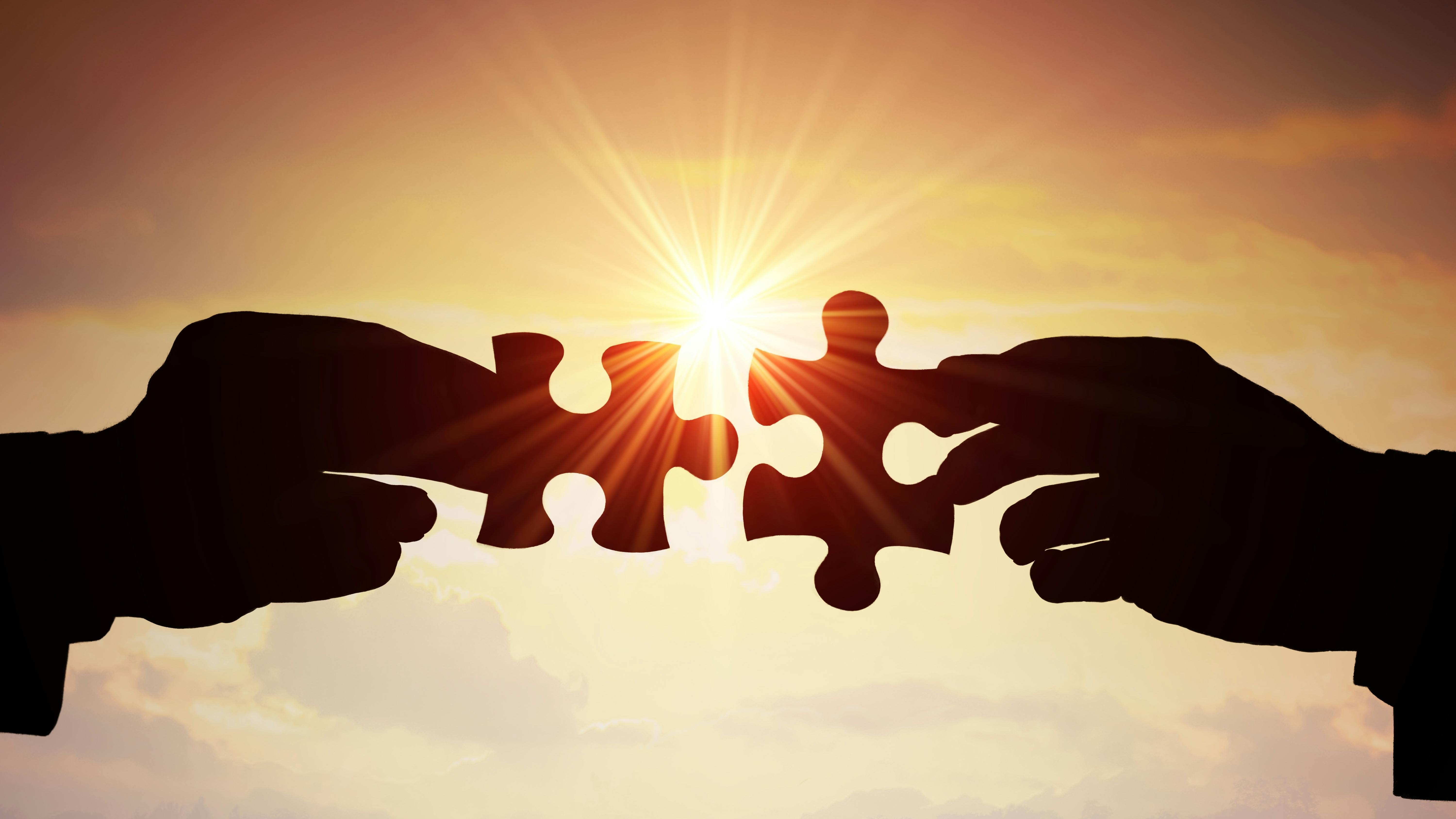 two hands holding puzzle pieces together