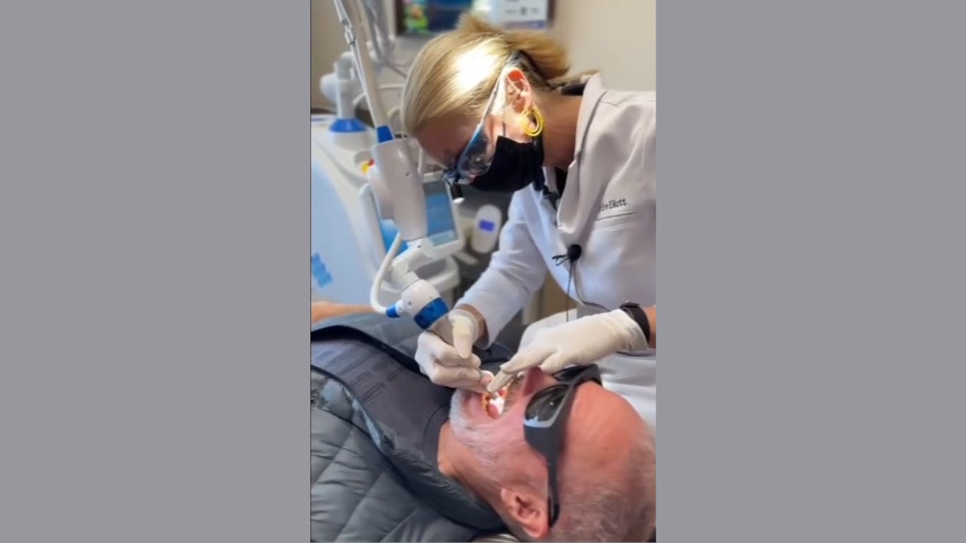 dentist using laser-assisted soft tissue therapy on a patient