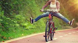 woman on a bicycle holding her legs out by the sides