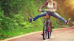 woman on a bicycle holding her legs out by the sides